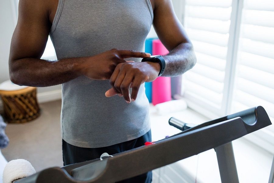 man on treadmill checking fitness watch